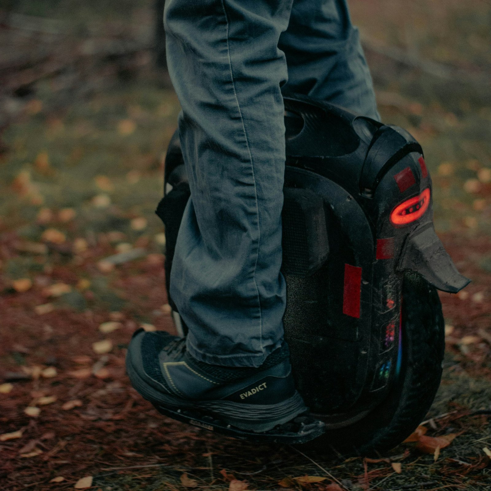 Electric unicycle with a red tail light on a forest path